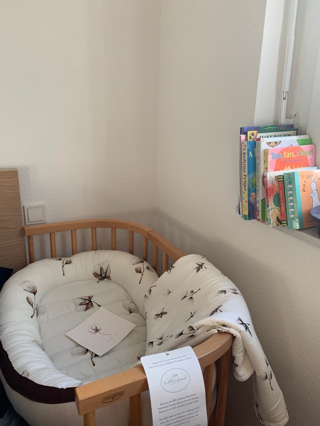 Photo of baby bassinet next to a large bed.