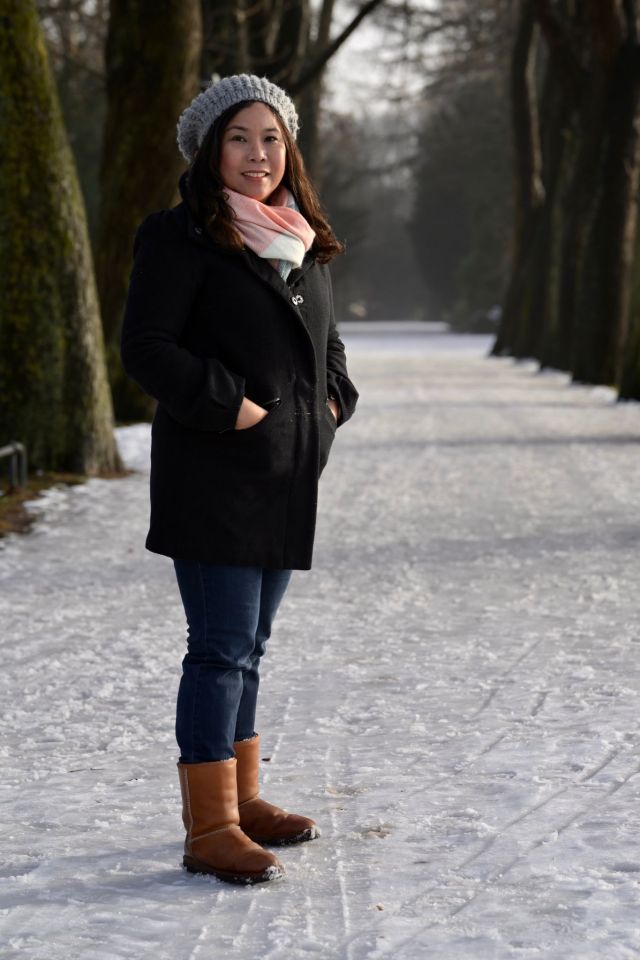 Woman posing amongst trees. Floor is covered in snow.