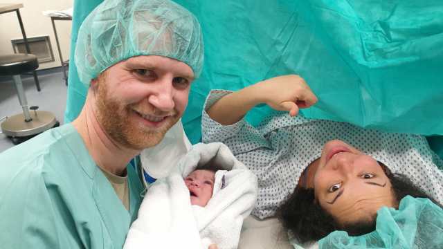 Man, woman and baby in the hospital after woman gave birth via c-section. Everyone is happy and smiling.